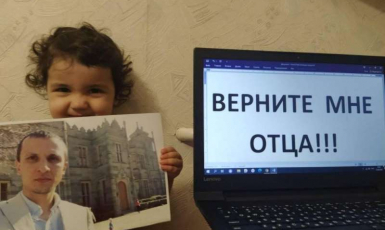 Nadzhiye Mustafayeva (youngest child of Server Mustafayev) with a photo of her father, next to the message Bring my father back Photo Crimean Solidarity